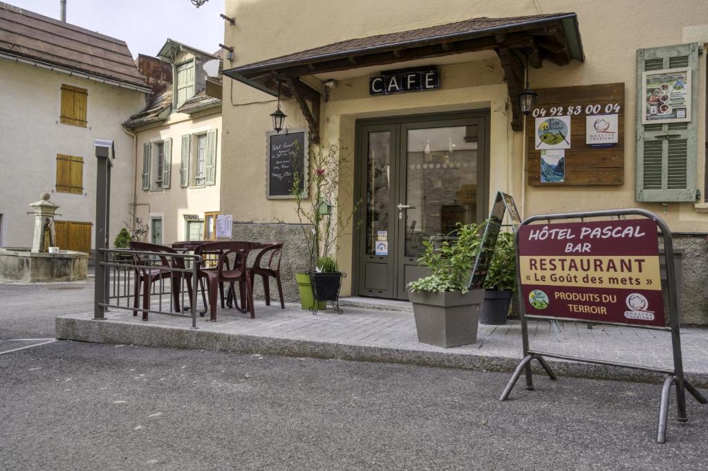 een café met tafels en een bord ervoor bij Hotel Pascal in Allos