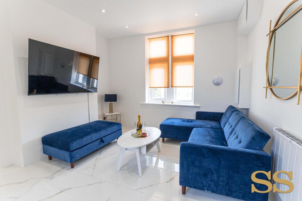 una sala de estar con 2 sofás azules y una mesa. en Blue Lagoon - 1 MINUTE FROM 02 ACADEMY - FREE PARKING - 5 MINUTES FROM THE BEACH - FAST WI-FI - SMART TV en Bournemouth