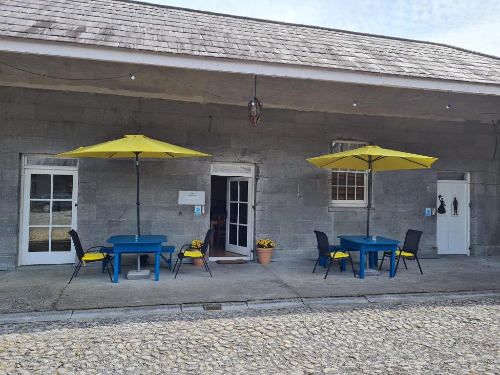 Oldcastle的住宿－Loughcrew Courtyard House，两把桌子和椅子,在大楼前摆放着黄伞