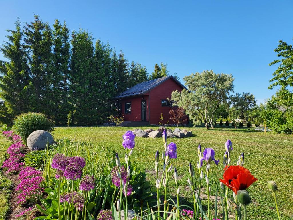 a garden with flowers in front of a red house at Kuusekoda in Käina