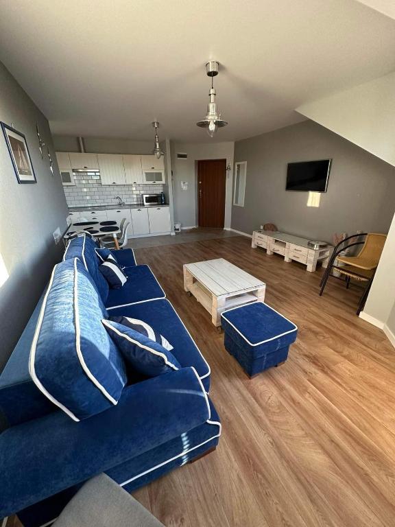 a living room with a blue couch and a kitchen at Apartament Albatros in Darlowko
