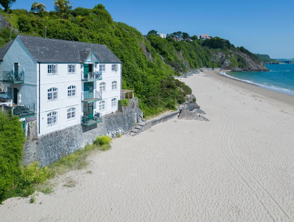 a white building on the beach next to the ocean at The Sand Castle - 2 Bedroom Apartment - Tenby in Tenby