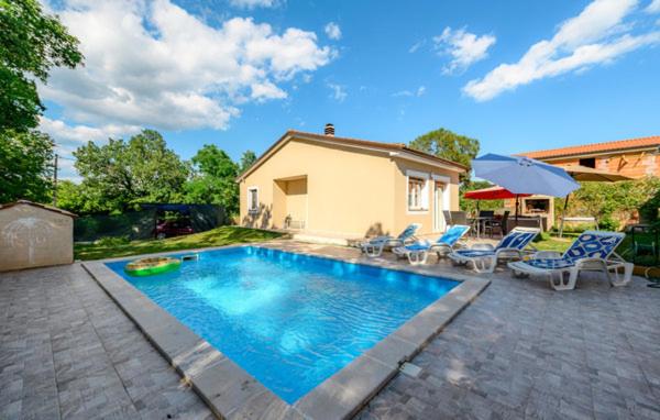 een zwembad met stoelen en een parasol en een huis bij Rovinj Mir in Matohanci