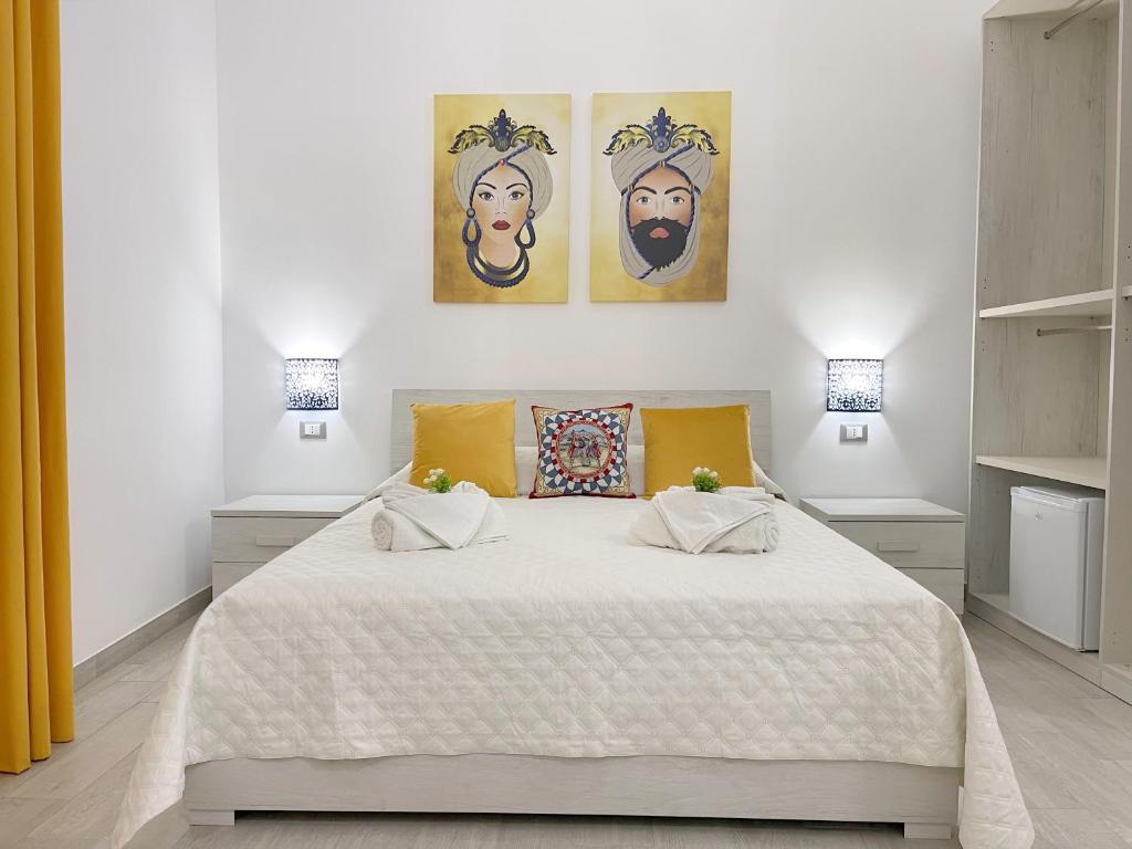 ein weißes Schlafzimmer mit einem großen Bett und gelben Kissen in der Unterkunft I MORI - Holiday Rooms in Lascari