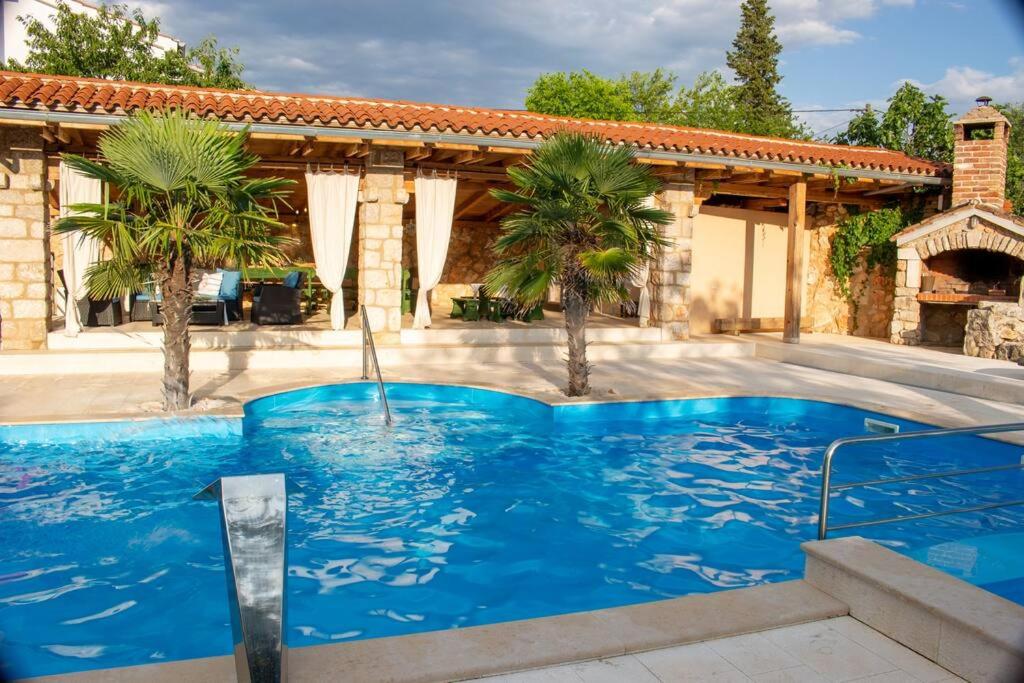 a swimming pool in the middle of a patio with palm trees at Entspannungsoase - Insel Krk in Rasopasno