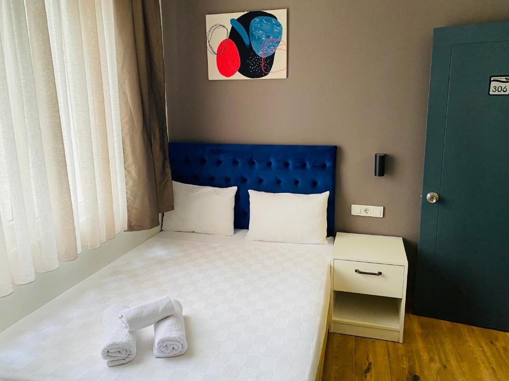 a small bedroom with a bed with a blue headboard at Turunç Hotel ANTALYA in Antalya