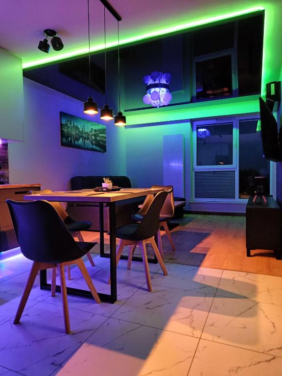 a dining room with a table and chairs and green lights at Luksusowy Apartament przy Galerii 8th floor in Kielce