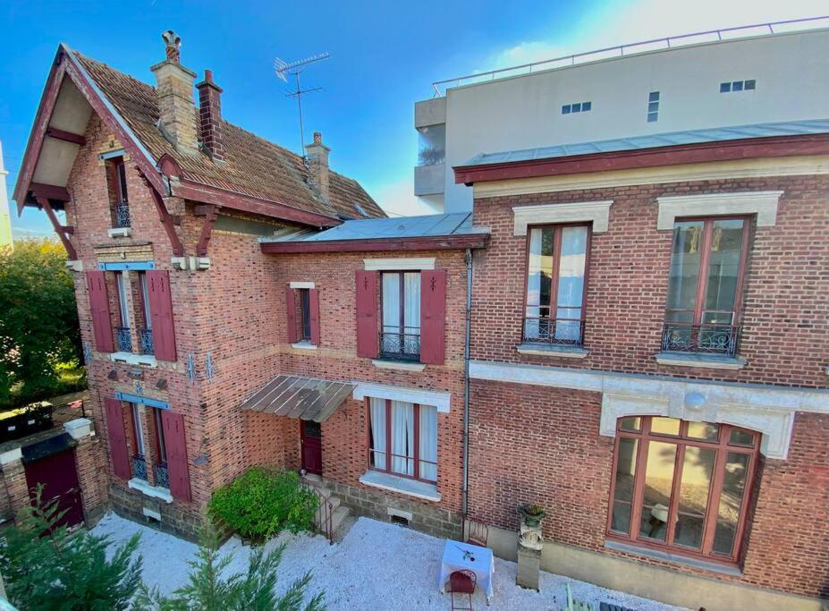 een oud bakstenen huis met rode ramen op een straat bij Big Maison 20 min Paris & Disney in Saint-Maur-des-Fossés