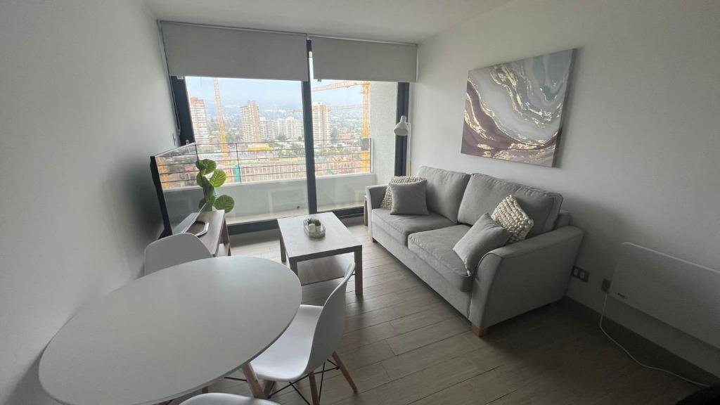 ein weißes Wohnzimmer mit einem Tisch und einem Sofa in der Unterkunft Departamento entero, cerca Plaza Egaña, Estacionamiento gratis in Santiago