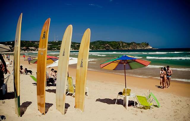 un groupe de planches de surf et de parasols sur une plage dans l'établissement Casa em Cond Geriba 400mt Praia com Espaço Gourmet, à Búzios