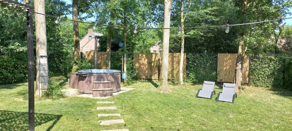 a backyard with two white chairs and a hot tub at Coco Wellness Bungalow in Ewijk