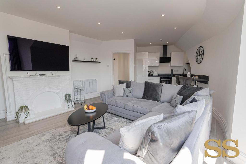 a living room with a couch and a table at Pearl Penthouse - 1 MINUTE FROM 02 ACADEMY - FREE PARKING - 5 MINUTES FROM THE BEACH - FAST WI-FI - SMART TV in Bournemouth