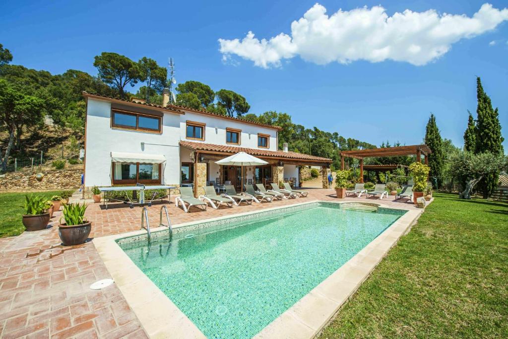 a villa with a swimming pool in front of a house at Can Lari Chalet in Vall-Llobrega