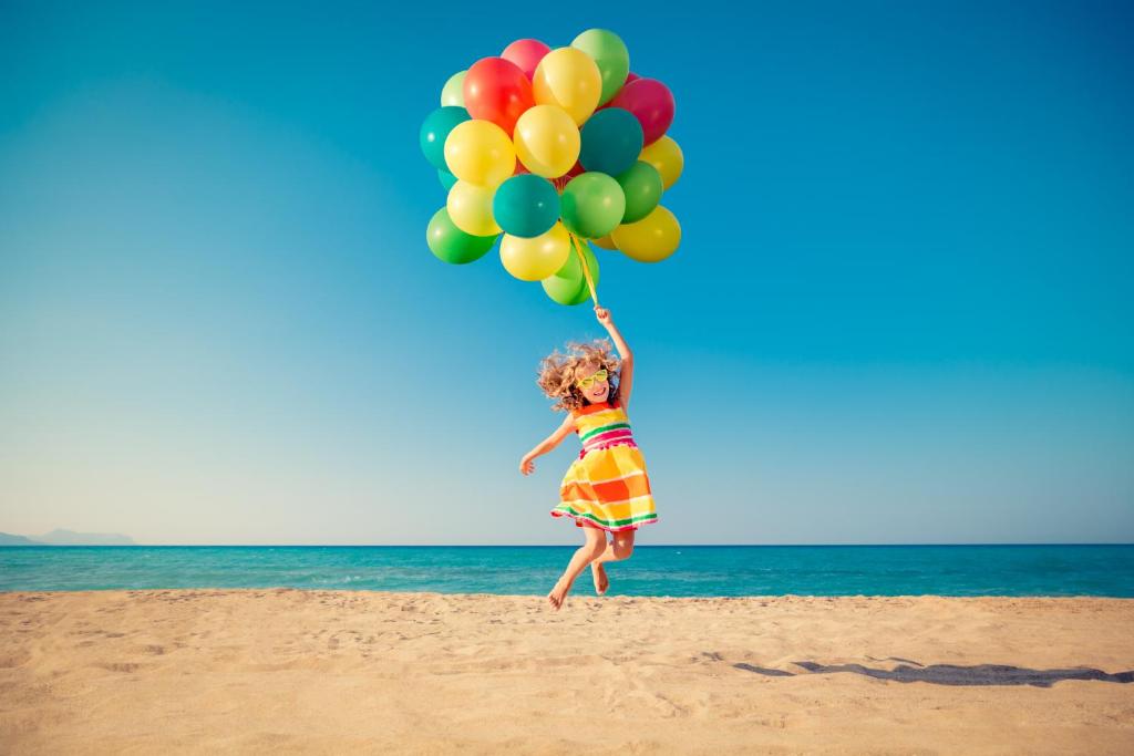 uma jovem saltando na praia segurando balões em Capo Vaticano Seaview Apartments em Capo Vaticano