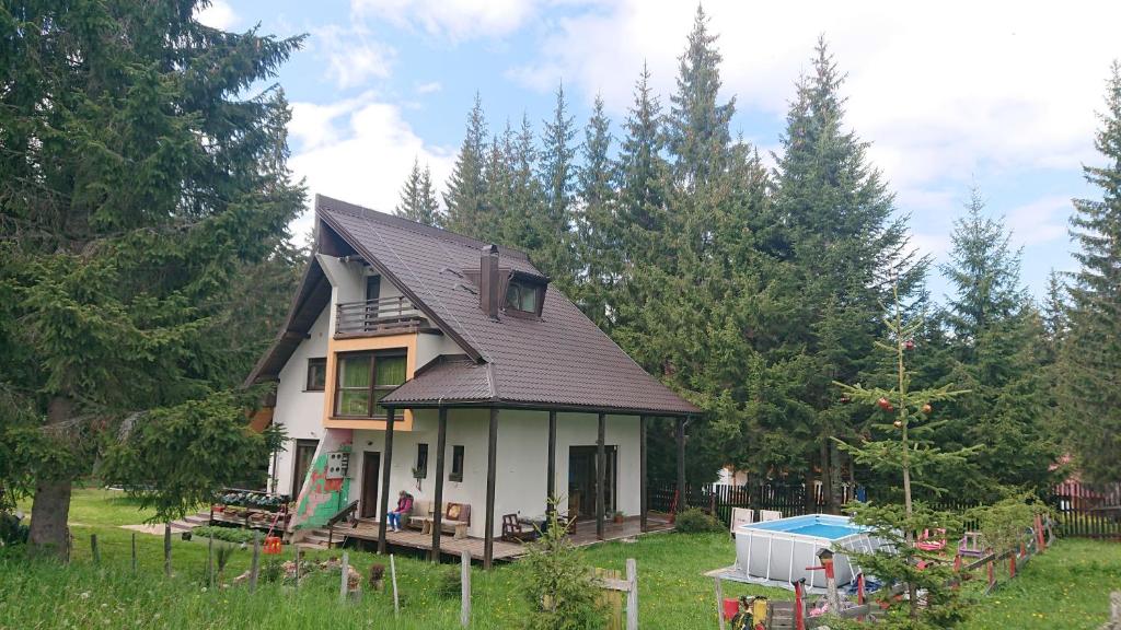 a white house with a black roof in a yard at House Apartments Jahorinko in Jahorina