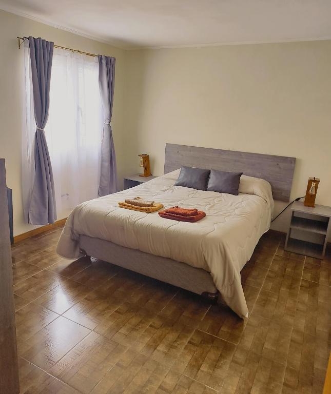 een slaapkamer met een groot bed en een houten vloer bij Alojamiento El Cóndor in Esquel