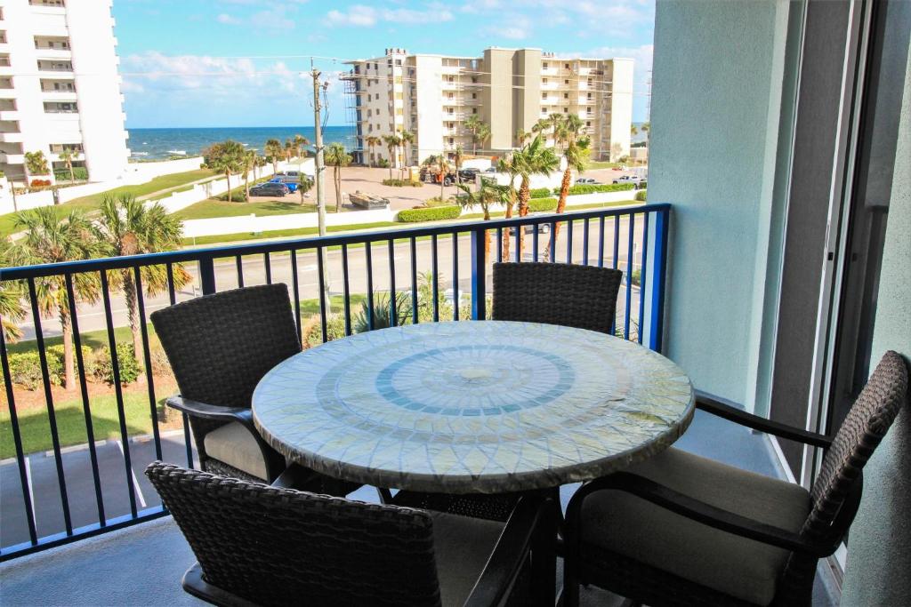 una mesa y sillas en un balcón con vistas al océano en Oceanwalk 13-406, en New Smyrna Beach