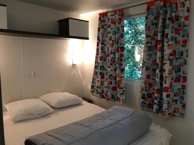 a bedroom with a bed and a window with curtains at Tahiti Village La Grande Côte in Saint-Palais-sur-Mer