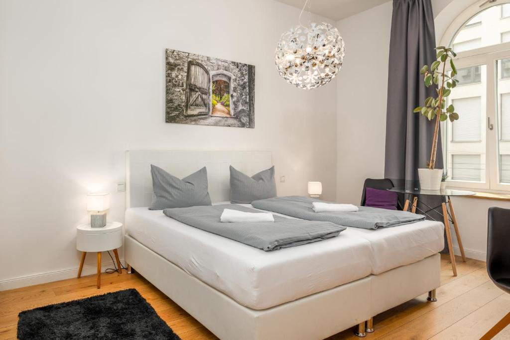 a bedroom with a large white bed and a chandelier at Apartments an der Arena Leipzig in Leipzig