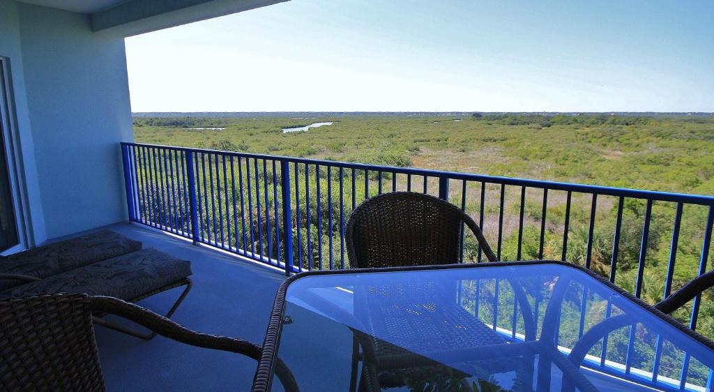 balcón con mesa de cristal, sillas y vistas. en Oceanwalk 9-604, en New Smyrna Beach