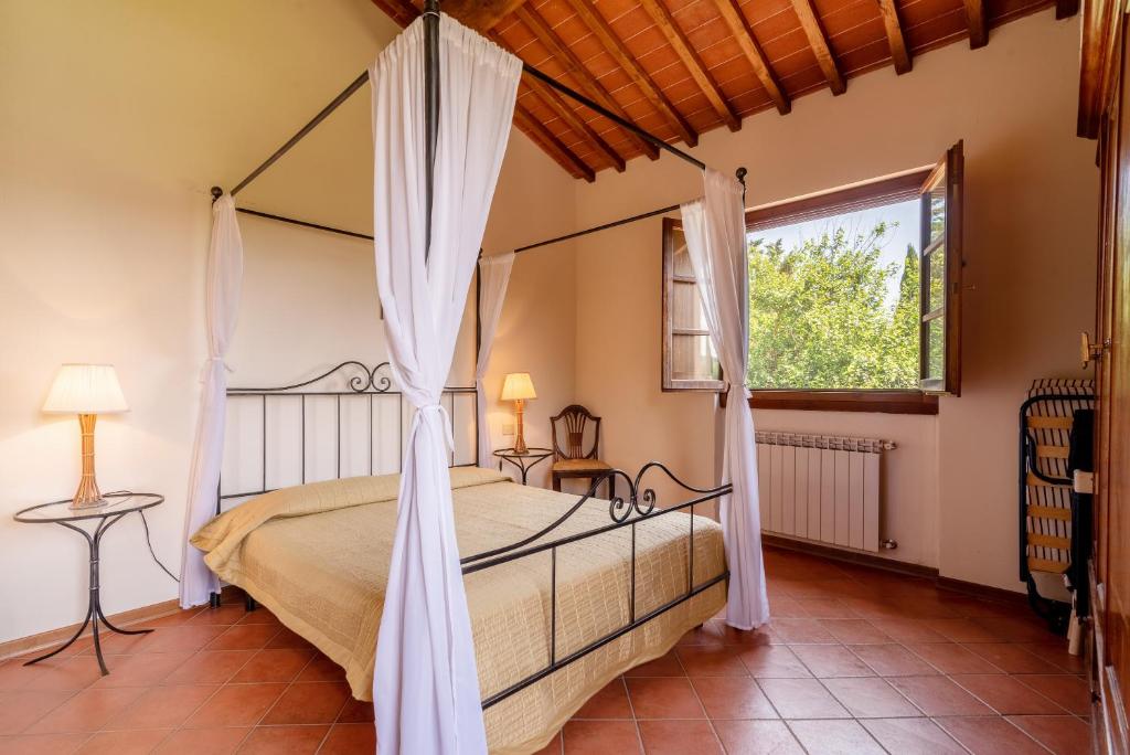 ein Schlafzimmer mit einem Himmelbett und einem Fenster in der Unterkunft Appartamento Colombaia in Laterina