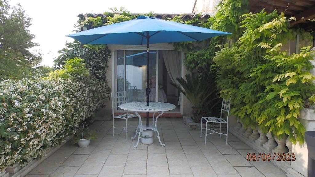 une table et des chaises avec un parasol sur une terrasse dans l'établissement Paradisiaque, à Brignoles