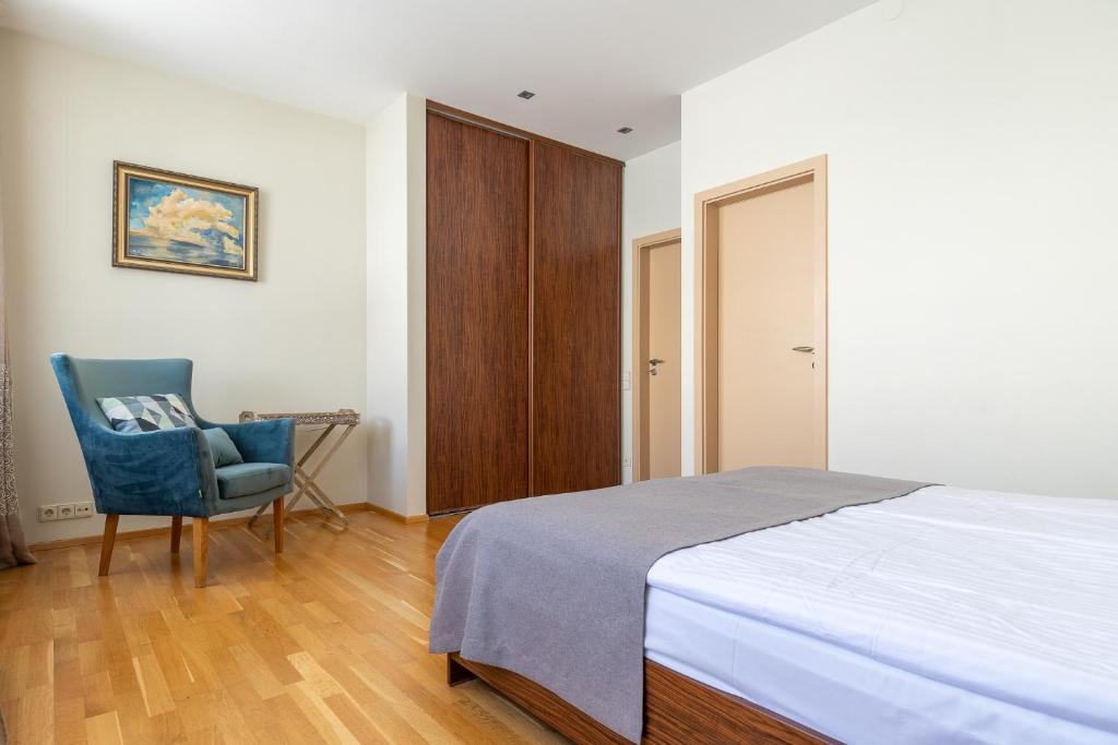 a bedroom with a bed and a blue chair at CAMELIA CENTRE APARTMENT in Palanga