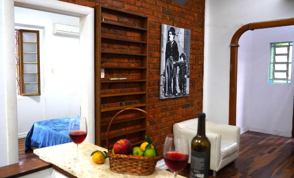 a counter with two glasses of wine and a basket of fruit at Casinha in Porto Alegre