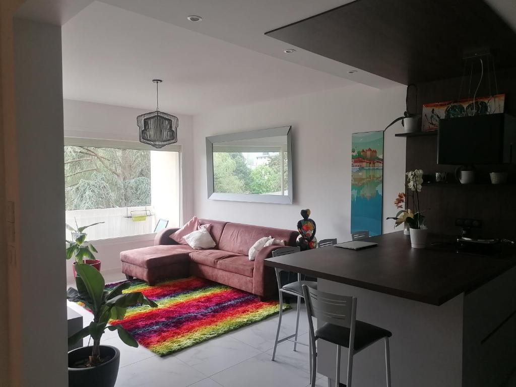 ein Wohnzimmer mit einem rosa Sofa und einem Tisch in der Unterkunft Appartement des Cygnes in Annecy