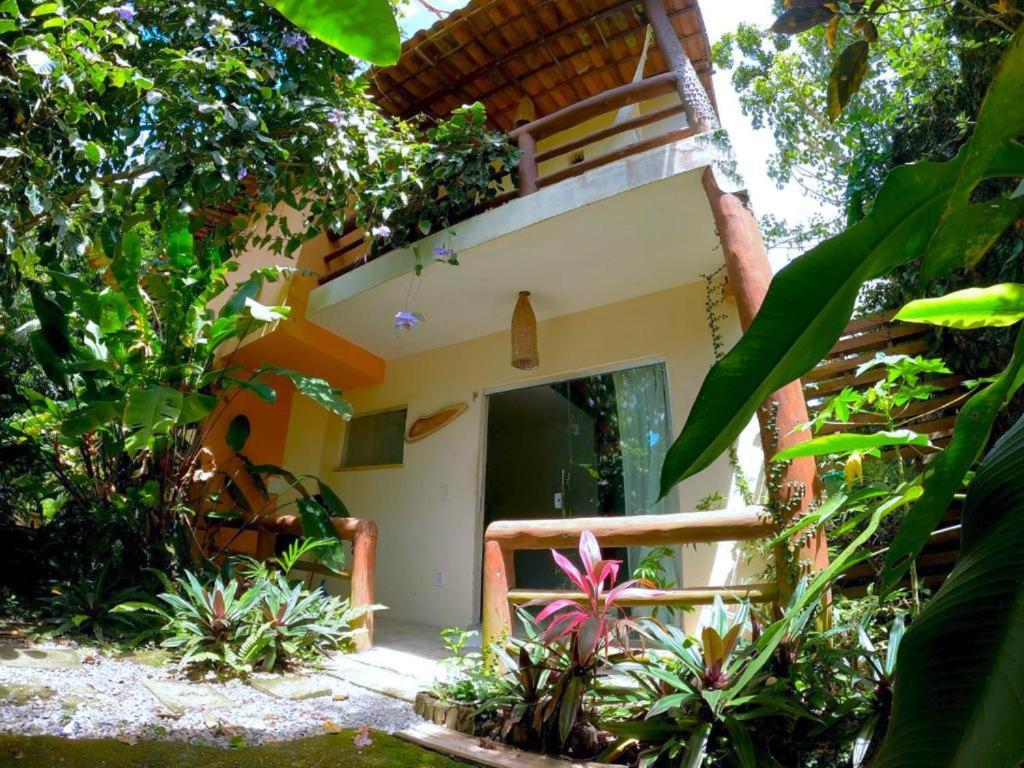 a house with a balcony and plants in front of it at Residencial Caetanos - 5 casas em Arraial D'ajuda in Porto Seguro