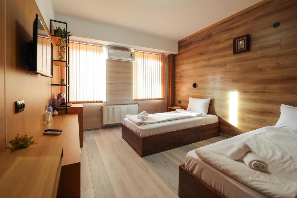 a bedroom with two beds in a room with wooden walls at Family Hotel Gotse Delchev in Gotse Delchev
