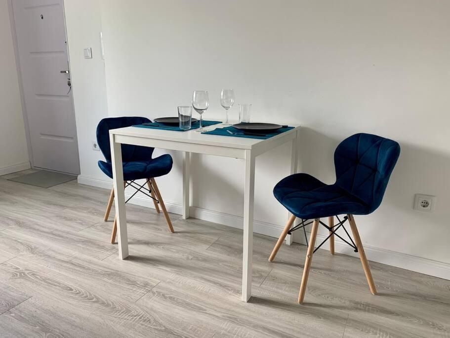 einen weißen Tisch mit zwei blauen Stühlen und Weingläsern in der Unterkunft Interno Casa in Sopron