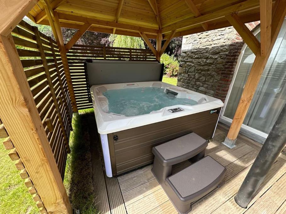 a hot tub sitting under a gazebo at Jacuzzi - Sauna - BBq - Jardin - Garden Lodge - Myosotis in Olne