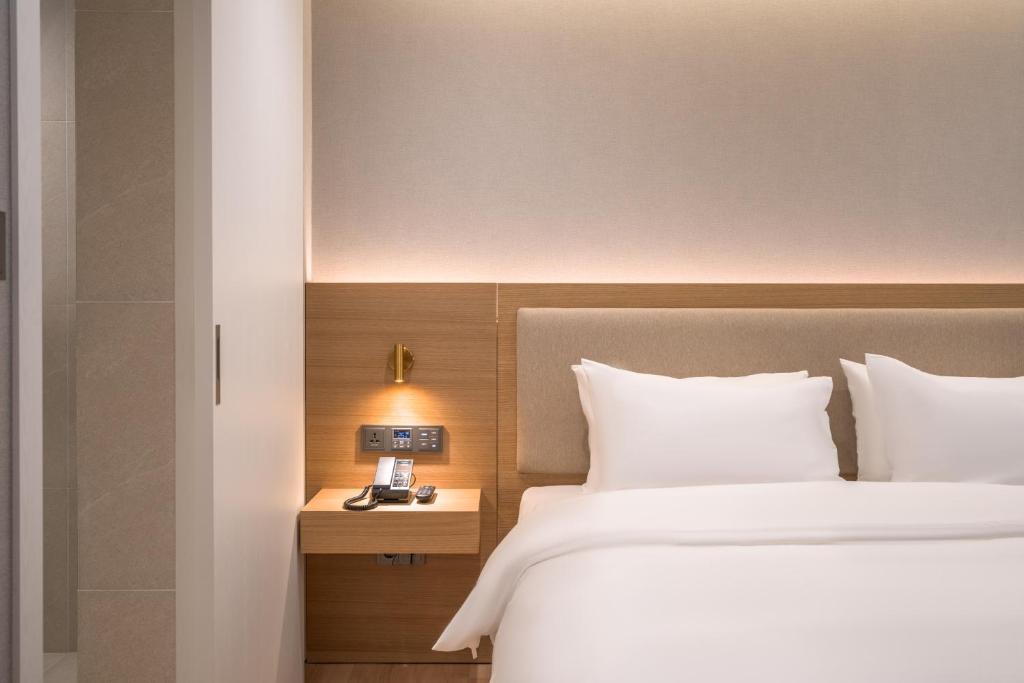 a hotel room with a bed and a night stand with a clock at Comfort inn Yeouido in Seoul