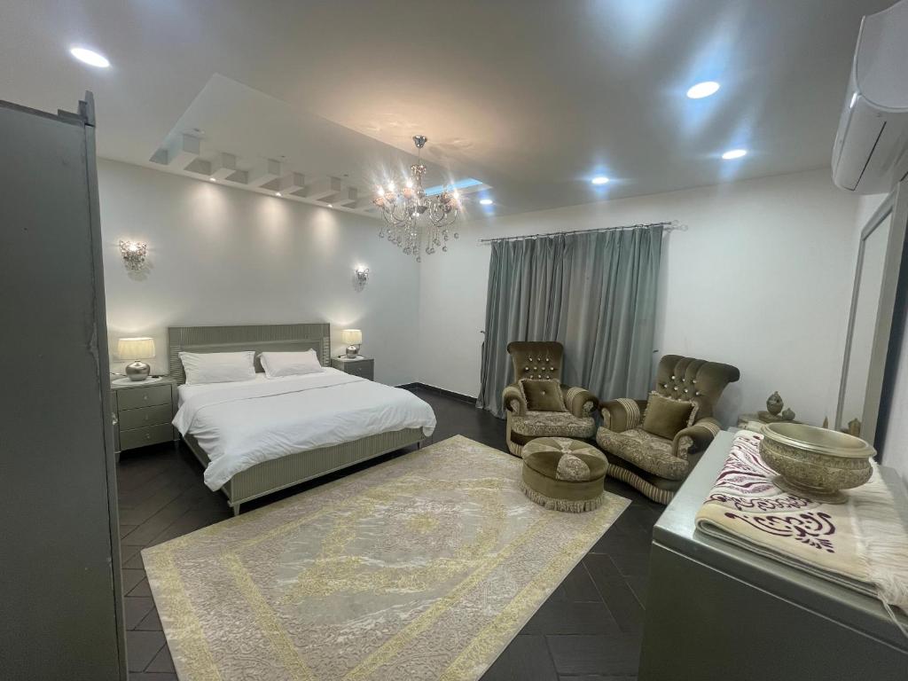 a bedroom with a bed and two chairs and a table at Beitk Al-ula Apartments شقق بيتك العلا in AlUla