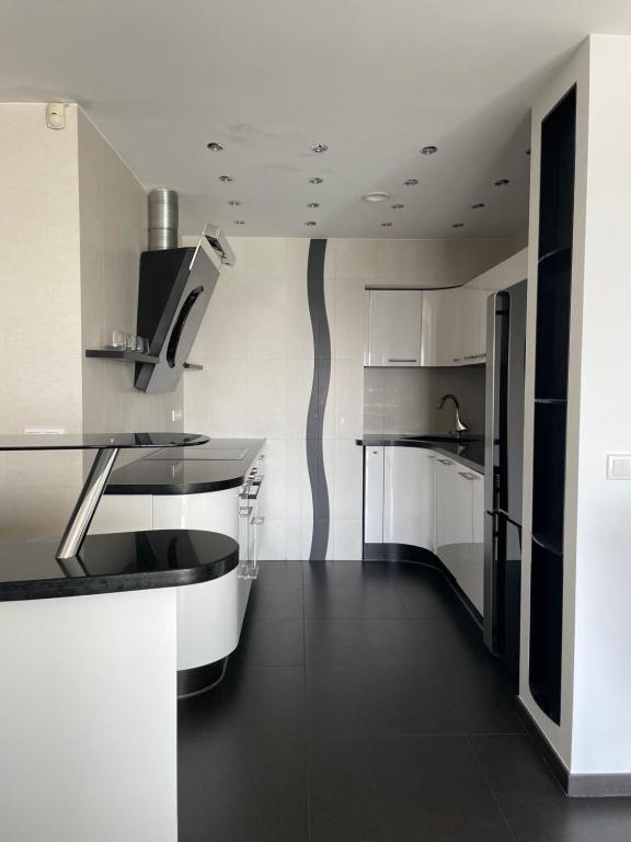 cocina con armarios blancos y suelo negro en Design apartment, en Klaipėda