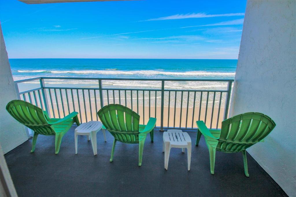 quatro cadeiras e uma mesa numa varanda com praia em Sea Coast Gardens III 303 em New Smyrna Beach