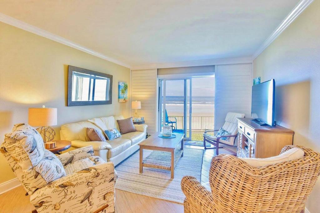 uma sala de estar com um sofá e uma televisão em Sea Coast Gardens II 105 em New Smyrna Beach