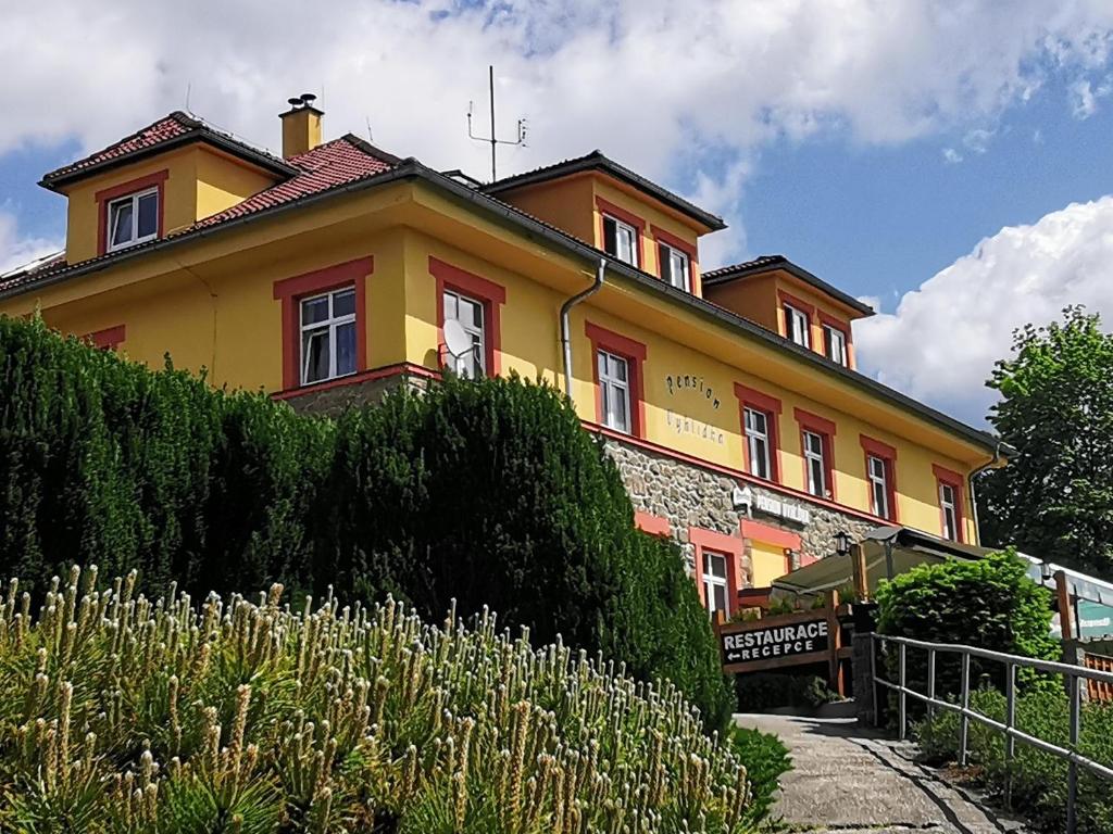 ein gelbes und orangefarbenes Haus auf einem Hügel in der Unterkunft Pension Vyhlídka in Přední Výtoň