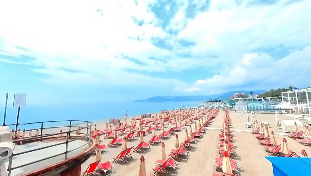 um monte de cadeiras de praia e guarda-sóis numa praia em Tra centro e mare - Intero appartamento con parcheggio em Savona