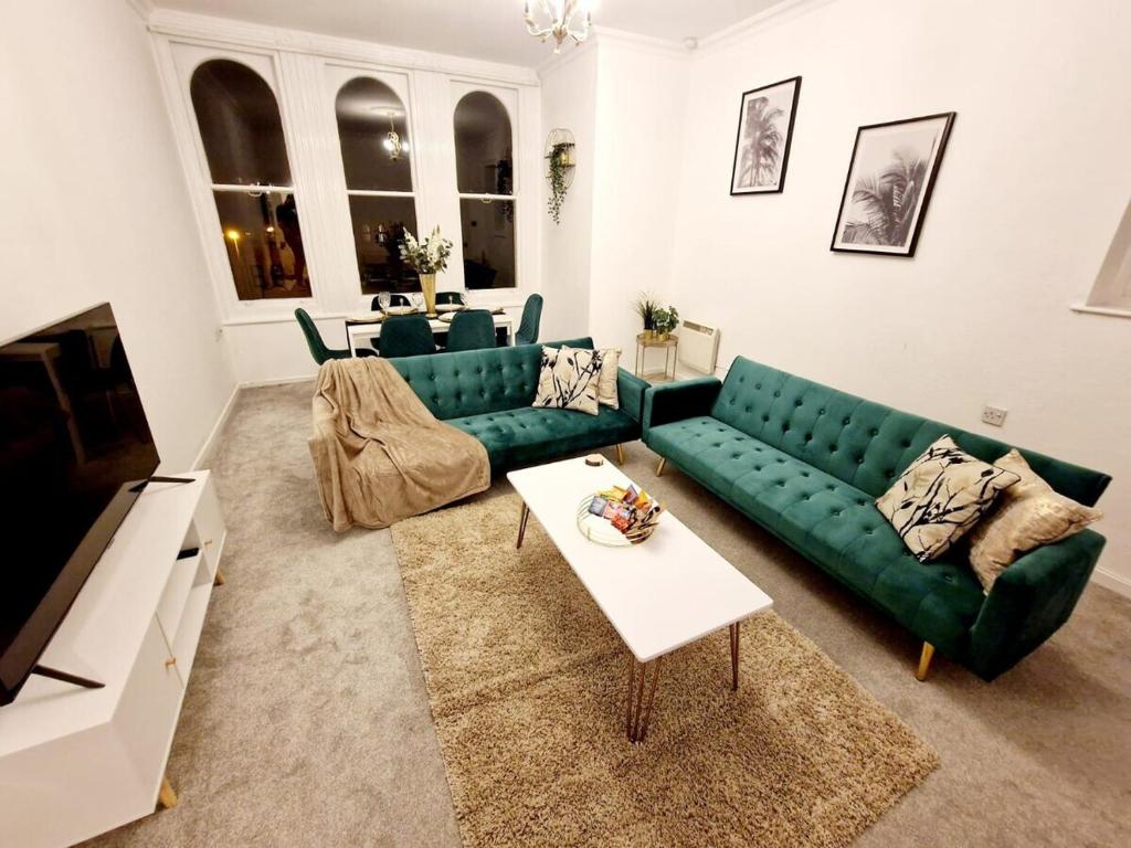 a living room with a green couch and a table at Two Bedroom Mansion House Apartment By AZ Luxury Stays Newmarket With Parking And WiFi in Newmarket