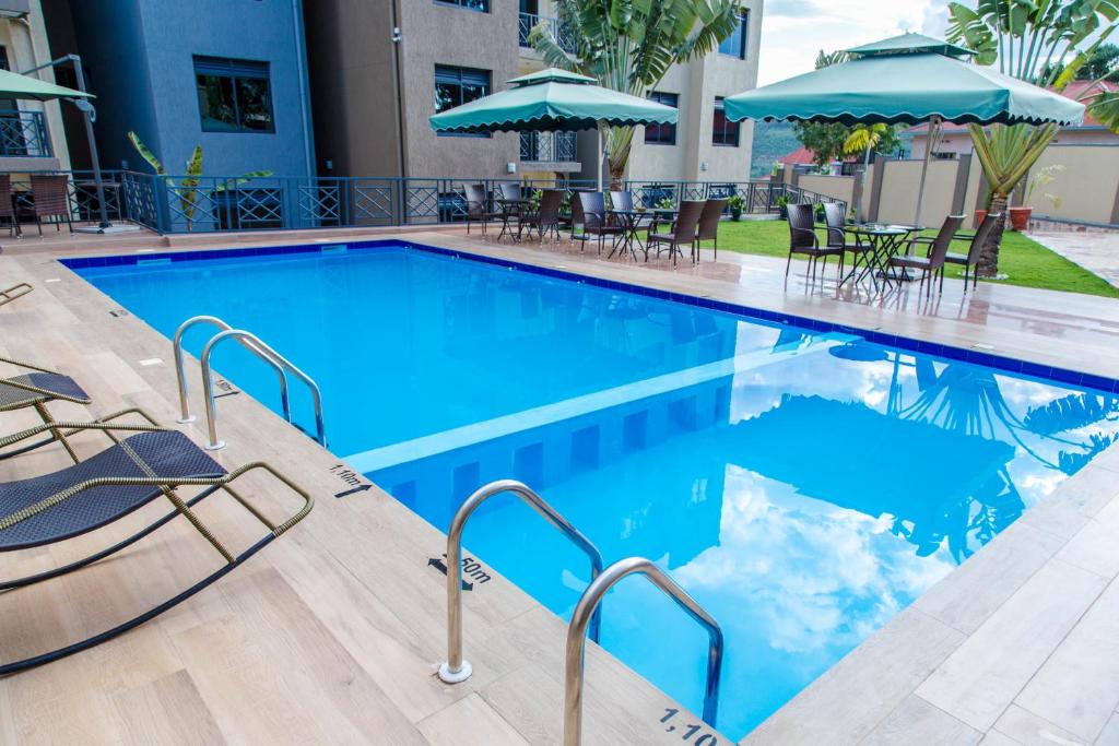 una piscina con sillas y sombrillas en un hotel en Mountain View Hotel & Apartment en Kigali