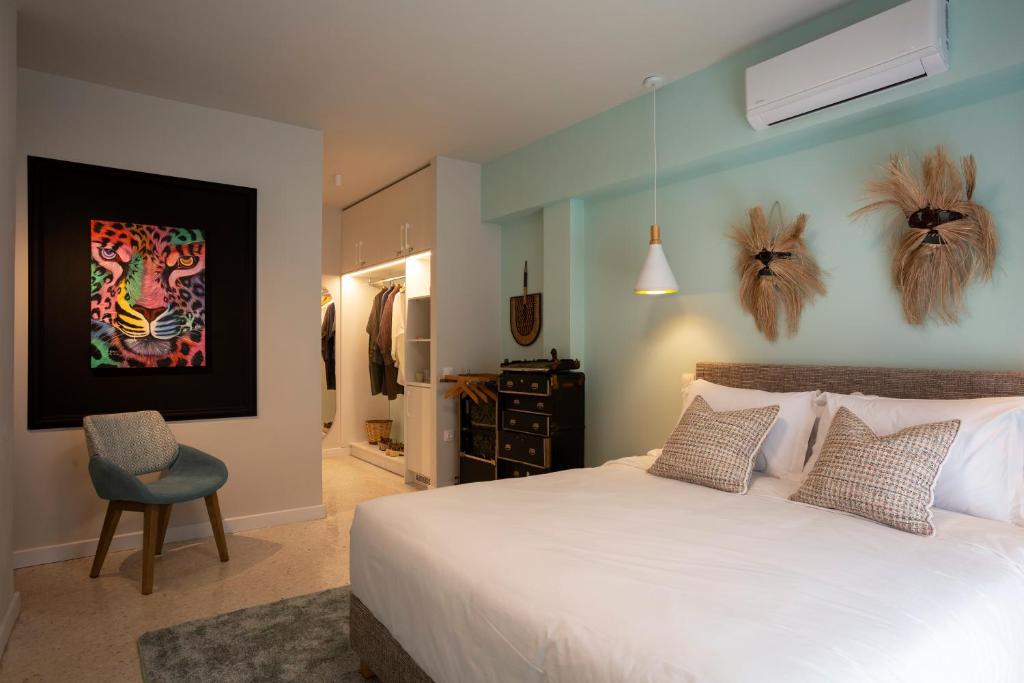 um quarto com uma grande cama branca e uma cadeira em The Frogs_Guest House em Atenas