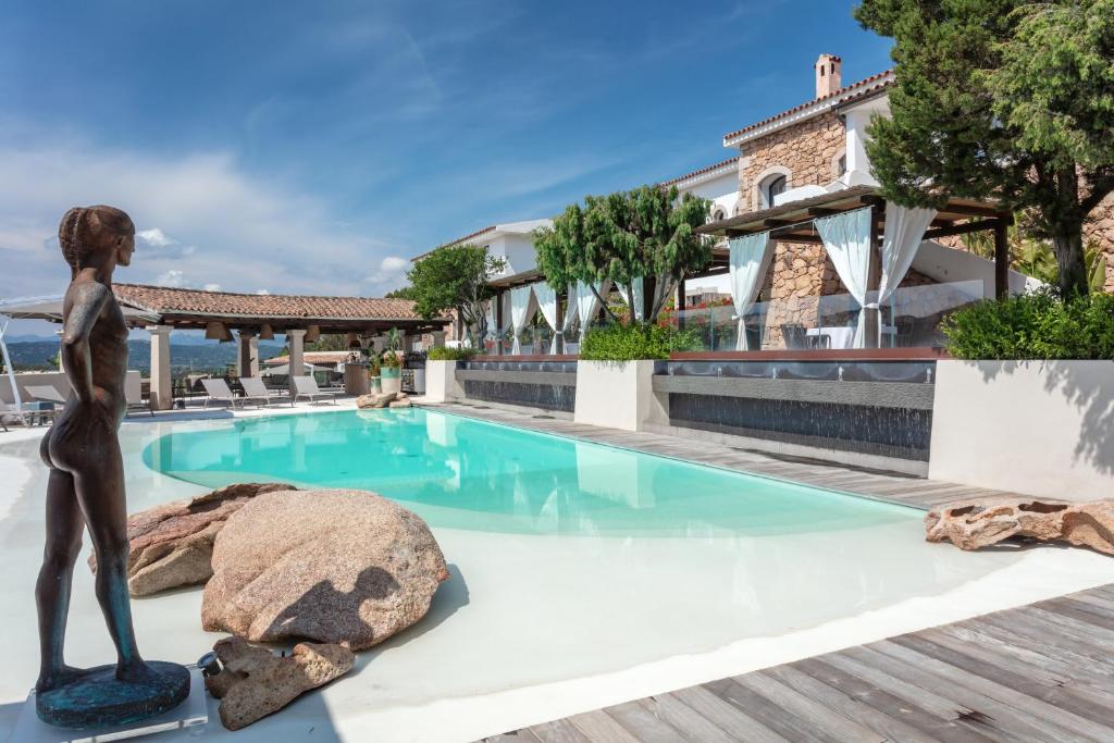 a statue of a girl standing on a rock next to a swimming pool at Hotel delle Rose in Porto Cervo