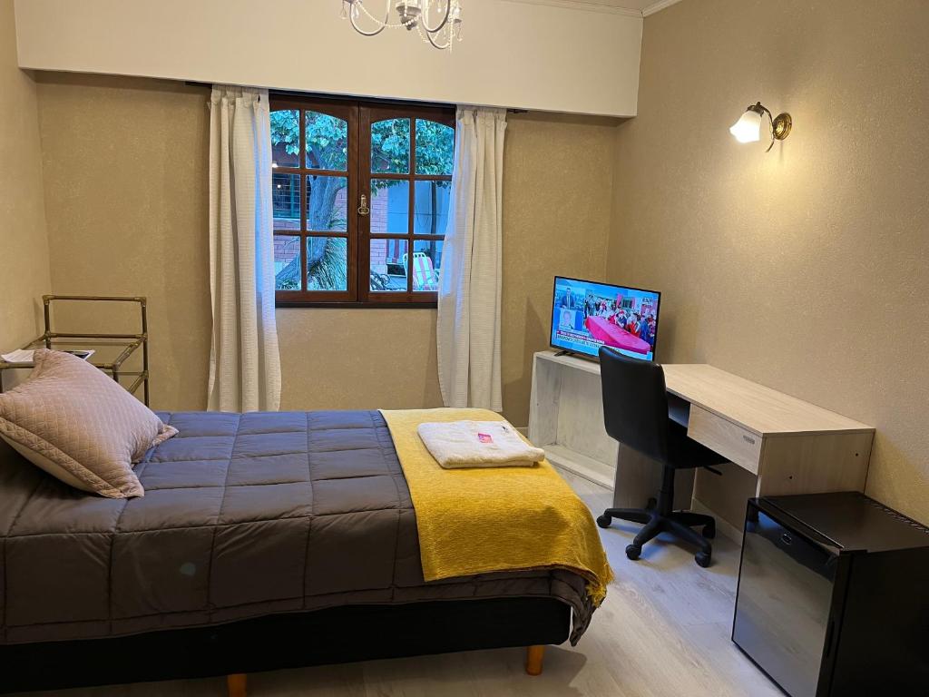 a bedroom with a bed and a desk and a television at SWEET HOME PATAGONIA in Comodoro Rivadavia