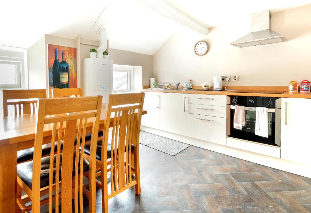 a kitchen with white cabinets and a table and chairs at Bridge Street in Aberystwyth