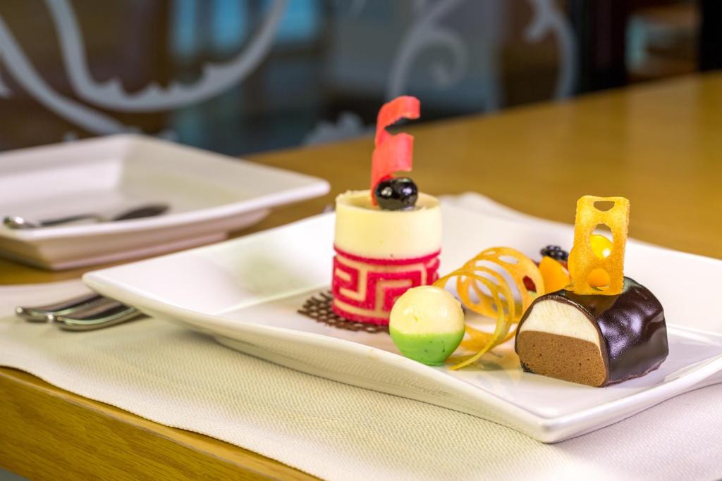 a white plate with a birthday cake on a table at Metropolitan Al Mafraq Hotel in Abu Dhabi