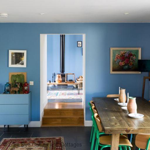 a dining room with a blue wall and a wooden table at Number 5 Steading Cottage in Banchory