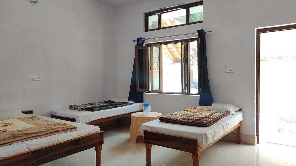 a room with two beds and a window at HOTEL PINE RESORT NETALA in Uttarkāshi