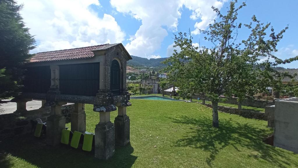 een tuin met een klein gebouw en een boom bij Casa de Santa Bárbara - Cinfães in Cinfães